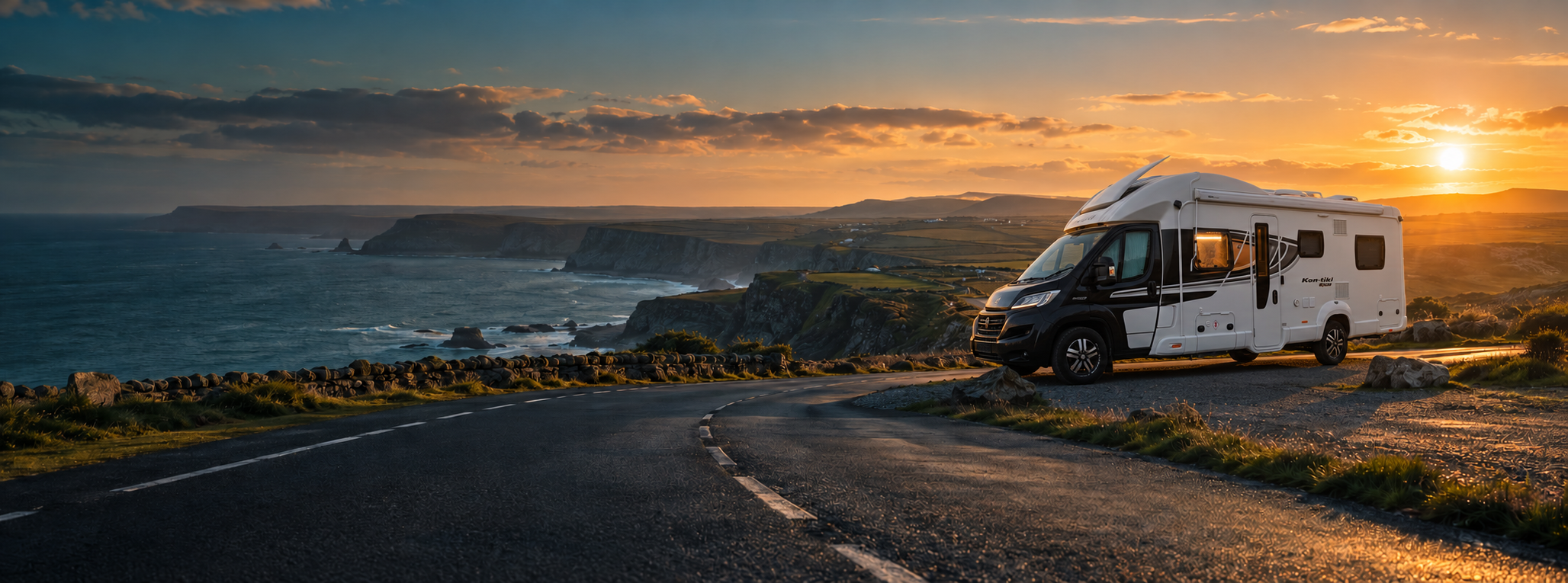 Marcus's black-and-white Swift Kon-Tiki motorhome overlooking a dramatic coastline at sunset